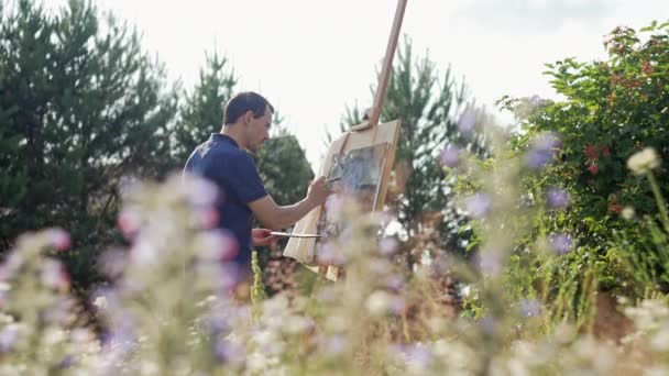 Male Artist Nature Paints Picture Surrounded Flowers Man Paints Brush — Vídeo de Stock