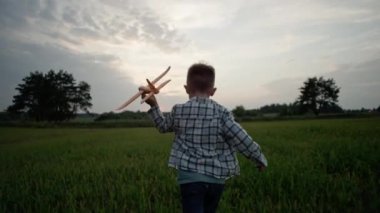 A child travels holding an airplane in his hands. A happy boy starts a plane in the park and dreams of becoming a pilot. Outdoor games that make a child happy and smiling. High quality 4k footage
