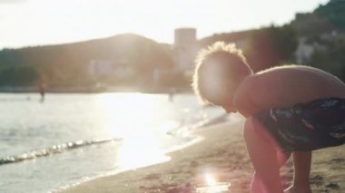A boy plays with toys on the beach in the sand. Happy childhood and cheerful child on the beach on vacation. High quality 4k footage