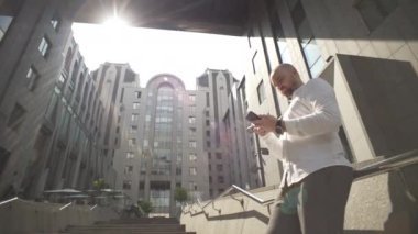 A businessman with a serious expression is writing a message on the phone. A man in casual clothes watches the stock market and conducts business using a smartphone. High quality 4k footage