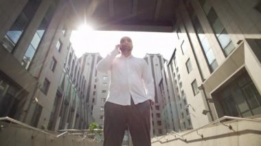 The manager is talking on the phone near the business center. A serious person solves cases and is nervous on the street. High quality 4k footage