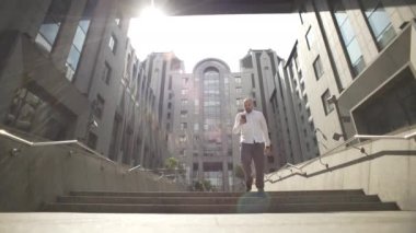 The manager goes and chats on the phone near the business center. A man solves work matters by typing on a smartphone. High quality 4k footage