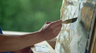 Close-up of an artists hands painting a picture with a brush. A man draws and looks for inspiration in nature. High quality 4k footage