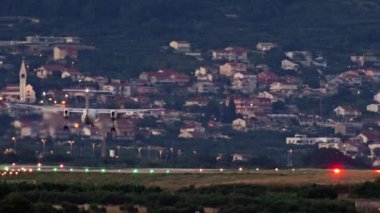 Uçak akşam havaalanının piste iniyor. Gün batımında arka planda şehir olan küçük bir uçağın yavaş çekim videosu. Şehir manzarası. Yüksek kalite 4k görüntü
