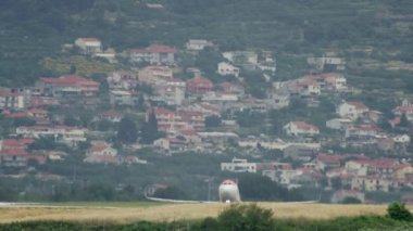Bir havaalanı pistinden şehir manzarasında bir uçak kalkıyor. Uçağın yerden kalkışının yavaş çekim videosu. Yüksek kalite 4k görüntü