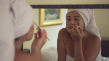 Avrupalı bir kız aynanın yanında gözlerini boyar. Havlu giymiş kadınlar evde makyaj yapıyor. Güzel bir kız bir restorana giden bir partiye hazırlanıyor. Yüksek kalite 4k görüntü