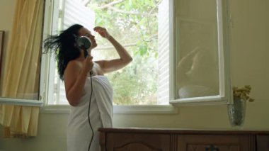 Kafkasyalı bir kızın saçlarını kurutma makinesiyle kuruturken çekilmiş yavaş çekim videosu. Havlu giymiş bir kadın güzelliğini giyer ve randevuya hazırlanır. Yüksek kalite 4k görüntü