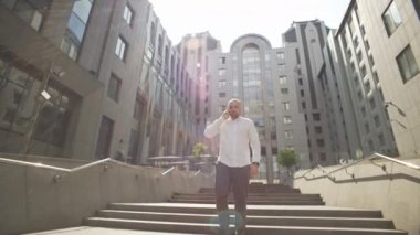 Günlük giysiler içinde bir iş adamı iş merkezinde dolaşıyor ve telefonda konuşuyor. Müdür öğle yemeğine giderken işlerle ilgilenir. Yüksek kalite 4k görüntü