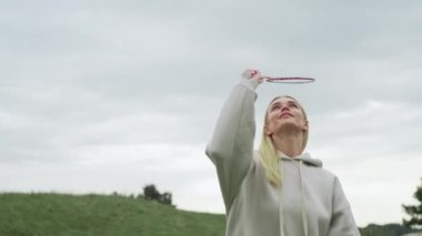 Parkta tenis oynayan güzel bir kadın. Raketli bir kız, Bambinton 'ı yürüyüşe çıkarıyor. Aktif yaşam tarzı. Yüksek kalite 4k görüntü