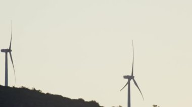 Gün batımında dönen yel değirmenlerinin yavaş çekim videosu. Enerji korunumu ve ekolojik elektrik kaynakları. Yüksek kalite 4k görüntü