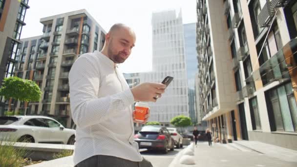 Biały Biznesmen Pijący Kawę Sms Ujący Przez Telefon Miejskim Krajobrazie — Wideo stockowe