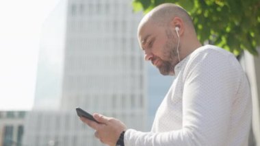 Günlük giysiler içinde, kulaklıkla müzik dinleyen ve kahve içen beyaz bir adam. Uçurumun kenarındaki bir işadamı rahatlar ve işi düşünür. Yüksek kalite 4k görüntü