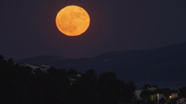 Dağlarda güzel bir dolunay var. Kanlı ay turuncu. Doğada ay ışığına yakın çekim. Yüksek kalite 4k görüntü