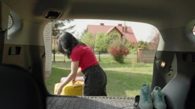 Kız bavulları bagaja koyar. Aile bir seyahate çıkıyor. Bir kadın bagajını arabaya koyar. Tatilden önce mutlu insanlar. Yüksek kalite 4k görüntü