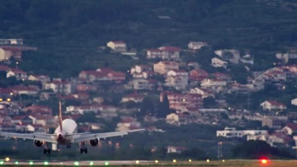 飛行機は日没時に空港に着陸する 旅客機と照明空港滑走路 高品質4K映像 — ストック動画