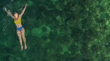Aerial view of a girl swimming in clear ocean water. An exotic and beautiful place where a woman swims on the sea. High quality 4k footage