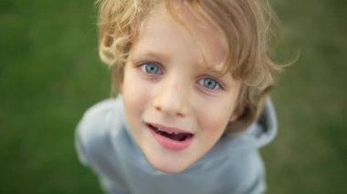 Beyaz, sevimli, gülümseyen çocuğun yakın çekimi. Çocuk bir kaput takar ve kameraya bakar. Mutluluk kavramı aşk ve çocuksu sevimlilik. Yüksek kalite 4k görüntü