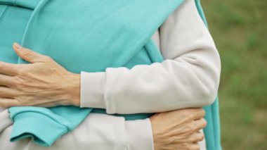 Yaşlı bir kadının ellerine ve yüzüne yakın çekim. Kadın kameraya gülümsüyor, güzel ve neşeli, orta yaşlı. Yüksek kalite 4k görüntü