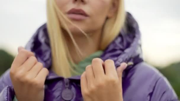 紫のダウンジャケットを着た白人モデルの肖像 美しい女の子がカメラを見ている 高品質4K映像 — ストック動画