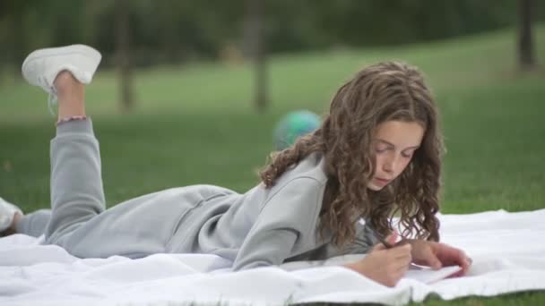 Vit Tonårstjej Som Studerar Parken Barnet Utför Uppgifter Och Skriver — Stockvideo