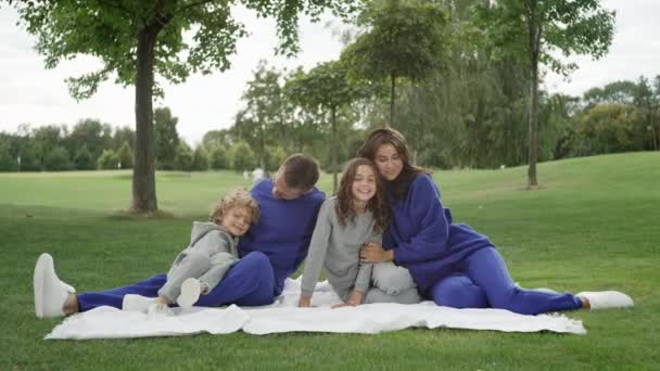 Счастливая Белая Семья Пикнике Парке Родители Дети Сидят Улыбаясь Обнимаясь — стоковое видео