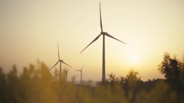 Gün batımında dağlarda rüzgar türbinlerine yakın çekim. Ekolojik elektriğin üretildiği rüzgâr çiftliğinden güzel bir manzara. Yüksek kalite 4k görüntü