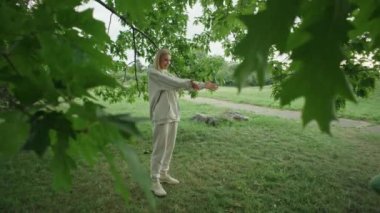 Anne kızını kollarında döndürüyor. Mutlu gülümseyen bir aile. Beyaz, sarışın kadın ve çocuk. Parkta yürüyor. Yüksek kalite 4k görüntü