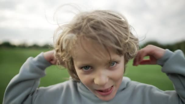 近くに男の子のカメラで笑みを浮かべてアップ 子供はフードを着る 幸福と喜びの笑顔の概念 高品質4K映像 — ストック動画