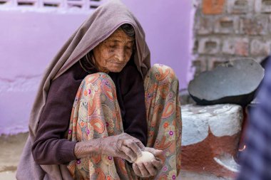 Hindistan 'daki Rajasthan, Hindistan' da ailesine yemek yapan yaşlı bir Hintli kadın.
