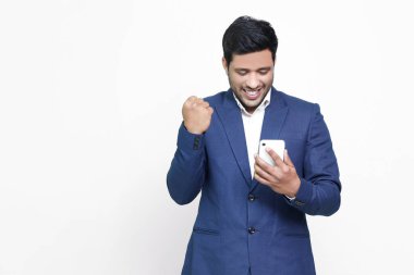 Heyecanlı Asyalı erkek izole edilmiş arka planda akıllı telefon kullanıyor..