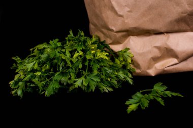 Taze sebzeli kağıt poşet. Pırasa, kırmızı dolma biber, maydanoz siyah arka planda bir kese kağıdında yatıyor..