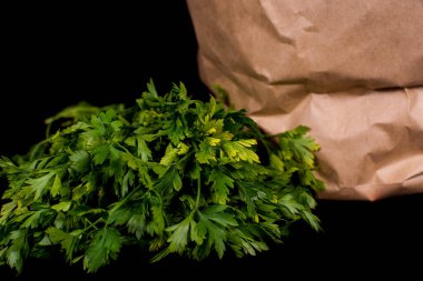 Taze sebzeli kağıt poşet. Pırasa, kırmızı dolma biber, maydanoz siyah arka planda bir kese kağıdında yatıyor..