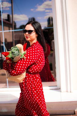 İyi alışverişler. Kırmızı elbiseli güzel beyaz bir kadının portresi. Elinde poşet dolusu alışveriş poşeti var..