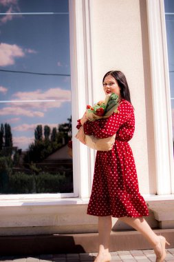 İyi alışverişler. Kırmızı elbiseli güzel beyaz bir kadının portresi. Elinde poşet dolusu alışveriş poşeti var..