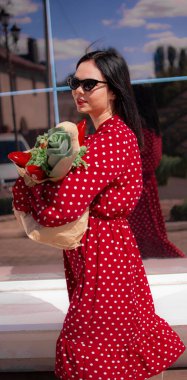 İyi alışverişler. Kırmızı elbiseli güzel beyaz bir kadının portresi. Elinde poşet dolusu alışveriş poşeti var..