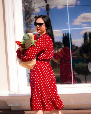 İyi alışverişler. Kırmızı elbiseli güzel beyaz bir kadının portresi. Elinde poşet dolusu alışveriş poşeti var..