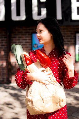 İyi alışverişler. Kırmızı elbiseli güzel beyaz bir kadının portresi. Elinde poşet dolusu alışveriş poşeti var..