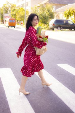 İyi alışverişler. Kırmızı elbiseli güzel beyaz bir kadının portresi. Elinde poşet dolusu alışveriş poşeti var..