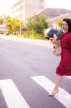 İyi alışverişler. Kırmızı elbiseli güzel beyaz bir kadının portresi. Elinde poşet dolusu alışveriş poşeti var..