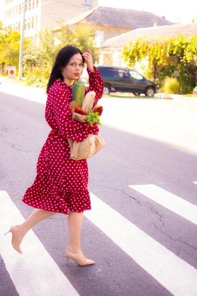 İyi alışverişler. Kırmızı elbiseli güzel beyaz bir kadının portresi. Elinde poşet dolusu alışveriş poşeti var..