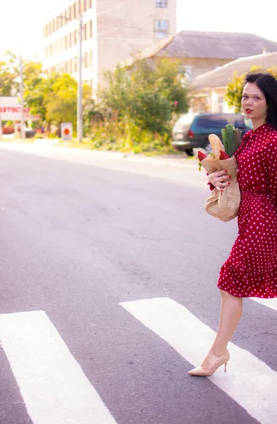 İyi alışverişler. Kırmızı elbiseli güzel beyaz bir kadının portresi. Elinde poşet dolusu alışveriş poşeti var..