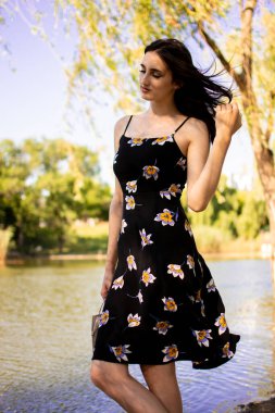 Şehir parkında yeşil çimlerin üzerinde uzanan neşeli, genç ve güzel bir kadın..