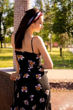 Şehir parkında yeşil çimlerin üzerinde uzanan neşeli, genç ve güzel bir kadın..