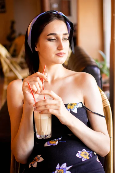 Kafede kahve içen genç bir kadının portresi.