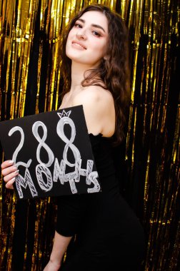 Altın arkaplan tatilinde siyah elbiseli kız..