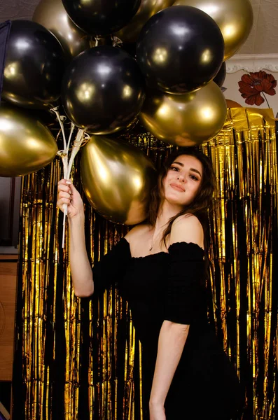 Uma Menina Vestido Preto Fundo Dourado Segura Balões Suas Mãos — Fotografia de Stock