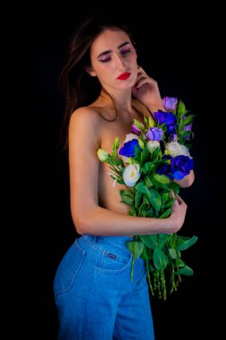 Brunette with flowers in her hands. young girl on a black background with flowers.