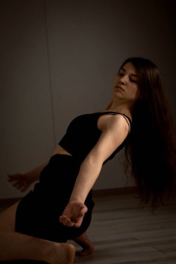 Kırmızı arka planda dans eden siyah dar takım elbiseli iki bale kızı.