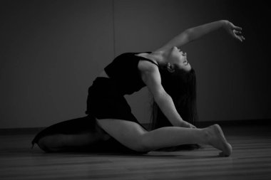 Kırmızı arka planda dans eden siyah dar takım elbiseli iki bale kızı.