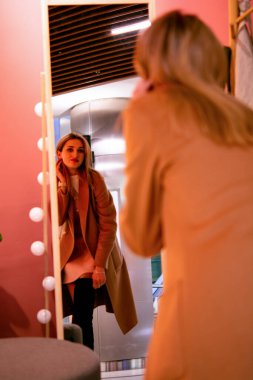 Genç bir kadın alışveriş torbaları tutarken kendinden geçmiş bir ifade sergiliyor.